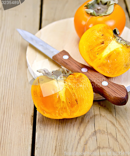 Image of Persimmon with knife on wooden board