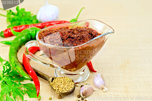 Image of Adjika in glass gravy boat with garlic on sacking