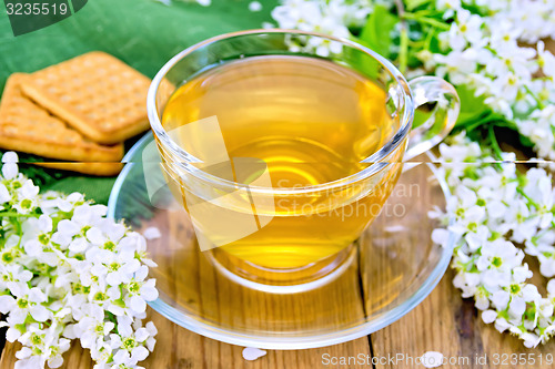 Image of Tea in cup with cookies and flowers of bird cherry on board