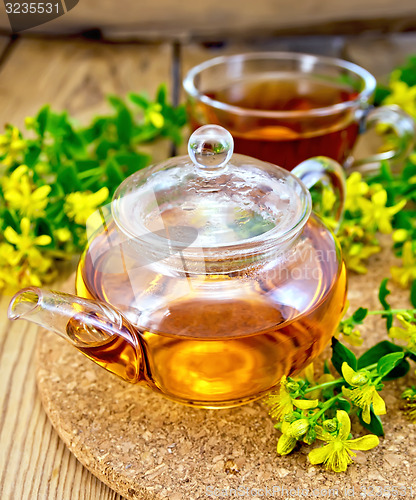 Image of Tea from tutsan in glass teapot and cup on board