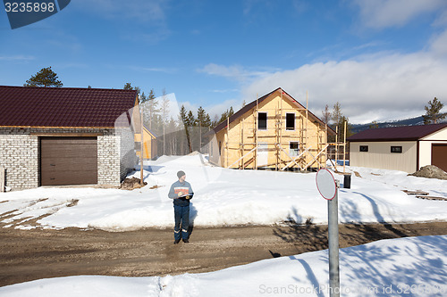 Image of Worker in overalls making notes on construction site