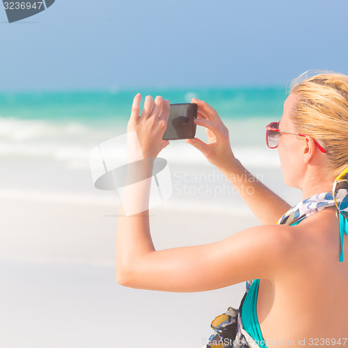 Image of Woman taking photo on the beach.