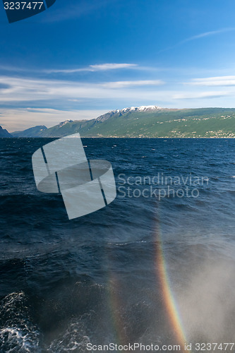 Image of rainbow on a lake Garda with mountains as background