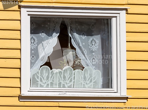 Image of window in a wooden house with white curtains