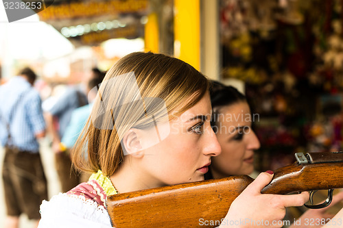 Image of Two attractive girls playing shooting games at German funfair