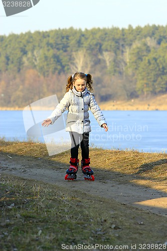 Image of young girl goes in roller skates on the ground