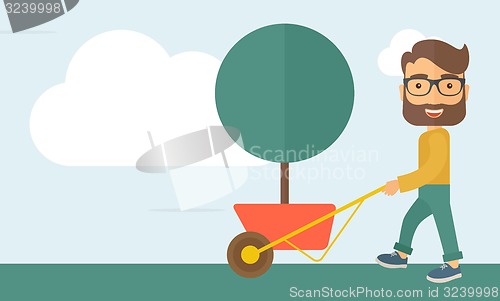 Image of Young man pushing the cart with tree.