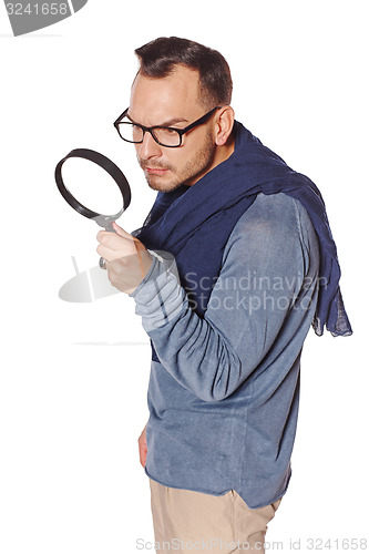 Image of Serious man looking through magnifying glass