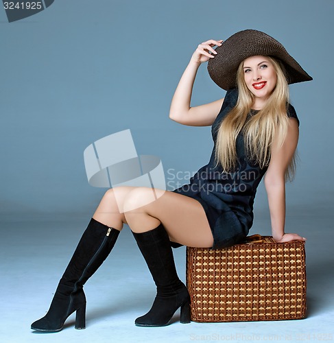 Image of Traveler woman sits on retro suitcase 