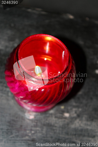 Image of church candle burning in red candlestick