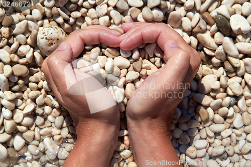 Image of Hands in the form of heart with pebbles inside
