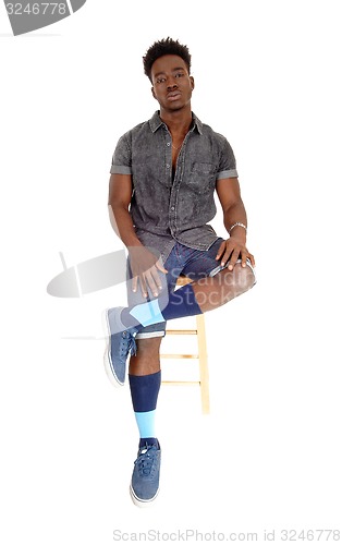 Image of Black man sitting on chair.