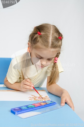 Image of Six year old girl sitting at the table and draws paints