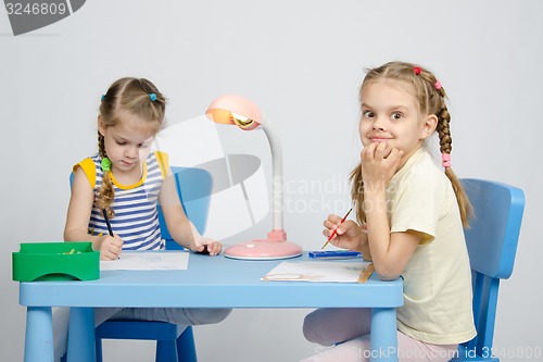 Image of Two sisters draw sitting at the table