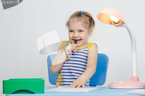 Image of Girl laughing stuck a pencil in her mouth