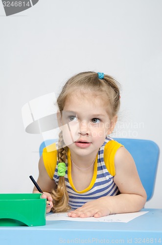 Image of The girl drawing with pencils at the table looked left