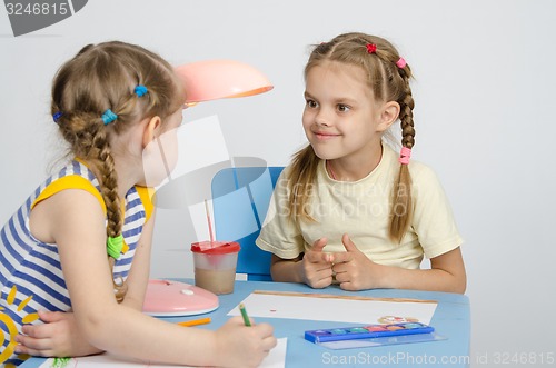 Image of Two girls drawing a table looking at each other