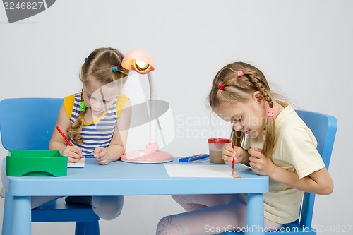 Image of Two girls drawing at table draw paints and pencils