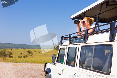 Image of Woman on safari looking through binoculars.