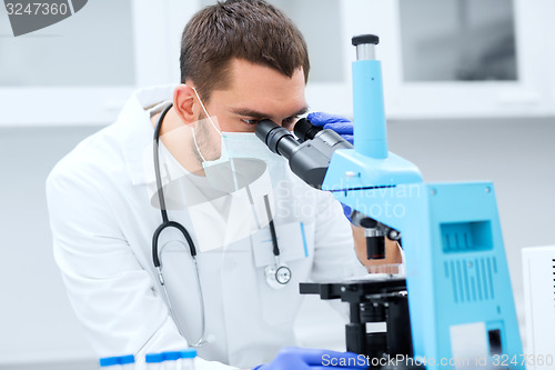Image of young scientist looking to microscope in lab
