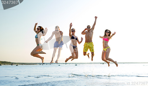 Image of smiling friends in sunglasses on summer beach