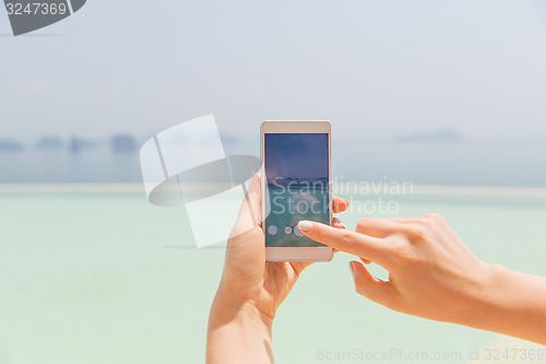 Image of close up of female hand with smartphone on beach