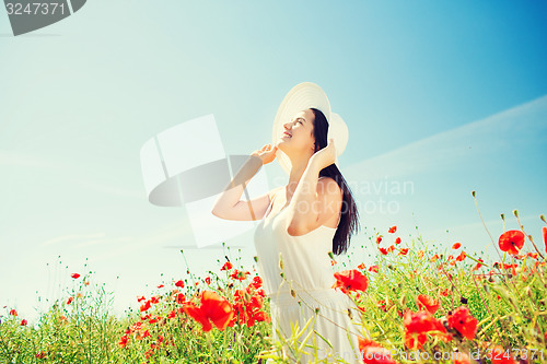 Image of smiling young woman in straw hat on poppy field