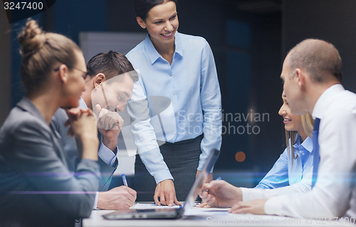 Image of smiling female boss talking to business team