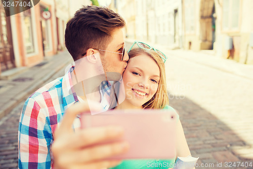 Image of smiling couple with smartphone in city