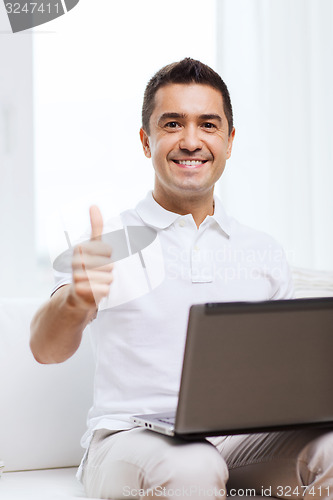 Image of happy man working with laptop computer at home