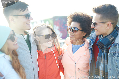 Image of happy teenage friends in shades talking on street