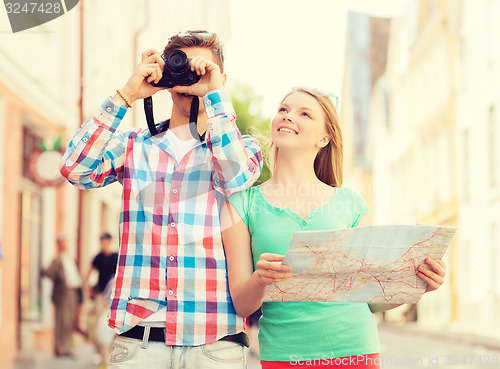 Image of smiling couple with map and photo camera in city