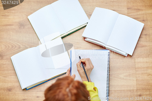 Image of close up of female hands writing to notebook