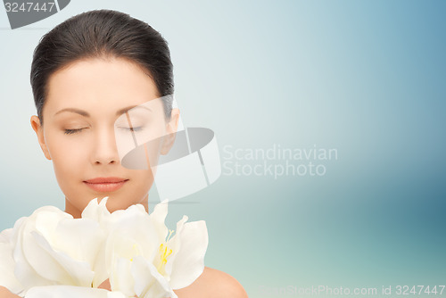 Image of beautiful woman smelling flowers with closed eyes