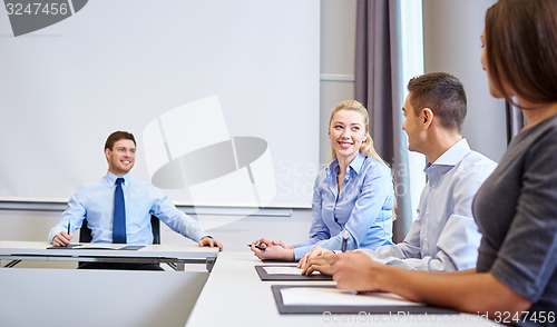 Image of group of smiling businesspeople meeting in office