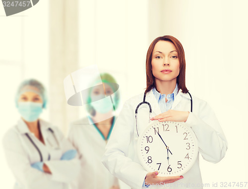 Image of calm female doctor with wall clock