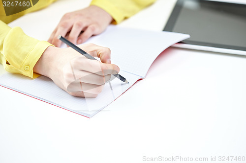 Image of close up of female hands writing to notebook