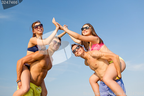 Image of smiling friends in sunglasses on summer beach