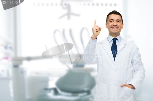 Image of smiling male dentist pointing finger up