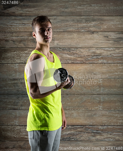 Image of young man with dumbbell flexing biceps