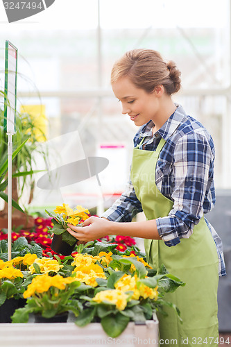 Image of happy woman holding flowers in greenhouse