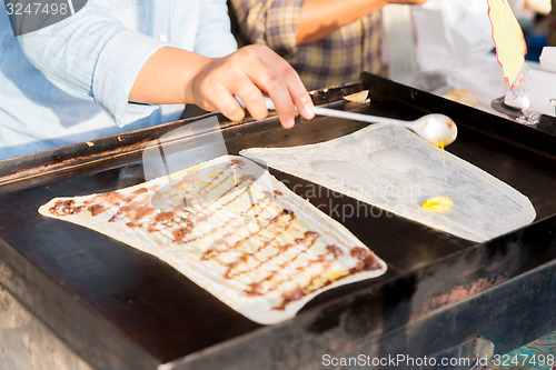 Image of close up of cook frying pancakes at street market