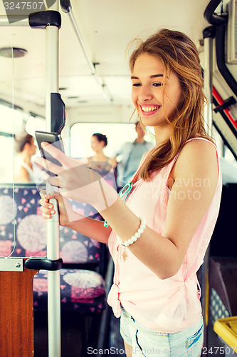 Image of smiling teenage girl with smartphone going by bus