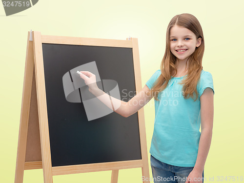 Image of happy little girl with blackboard and chalk