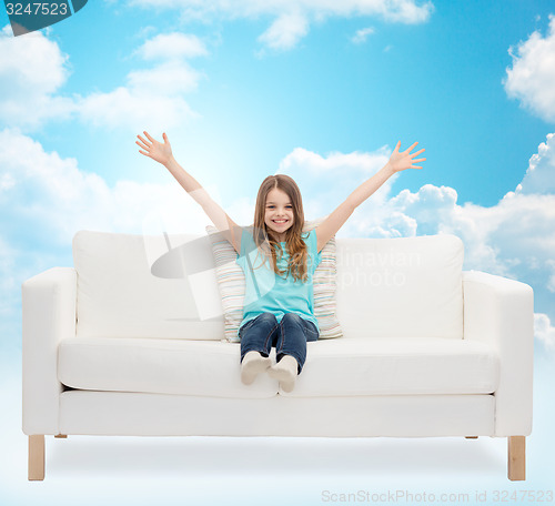 Image of happy girl sitting on sofa with raised hands