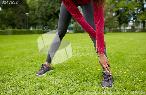 Image of close up of woman stretching leg outdoors