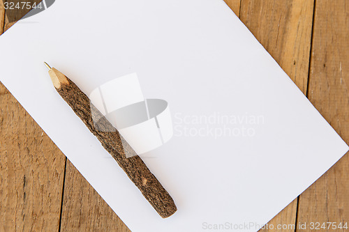 Image of white blank paper sheet with wooden pen on table 