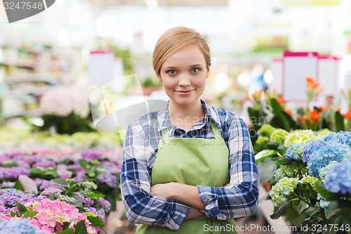 Image of happy woman with flowers in greenhouse