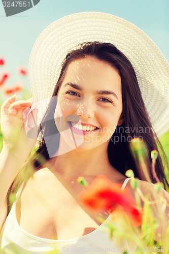 Image of smiling young woman in straw hat on poppy field