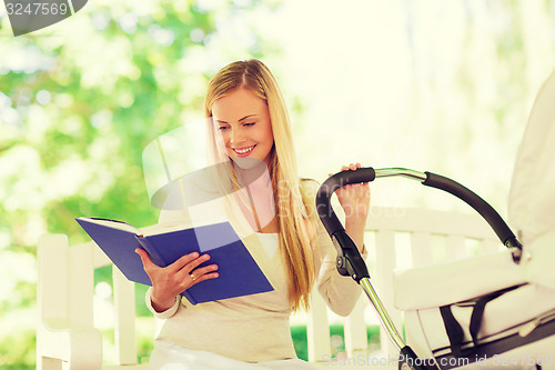 Image of happy mother with book and stroller in park